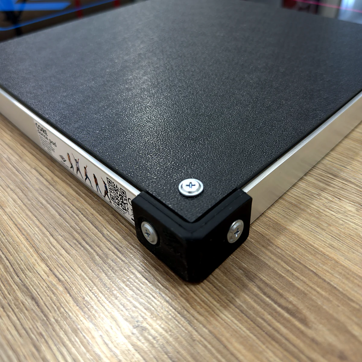 sq-ltek-core-aluminium-frame-corner - Interactive Mats L-TEK Close-up of the aluminium frame, screwed panel and black corner protector of the L-TEK Core dance pad