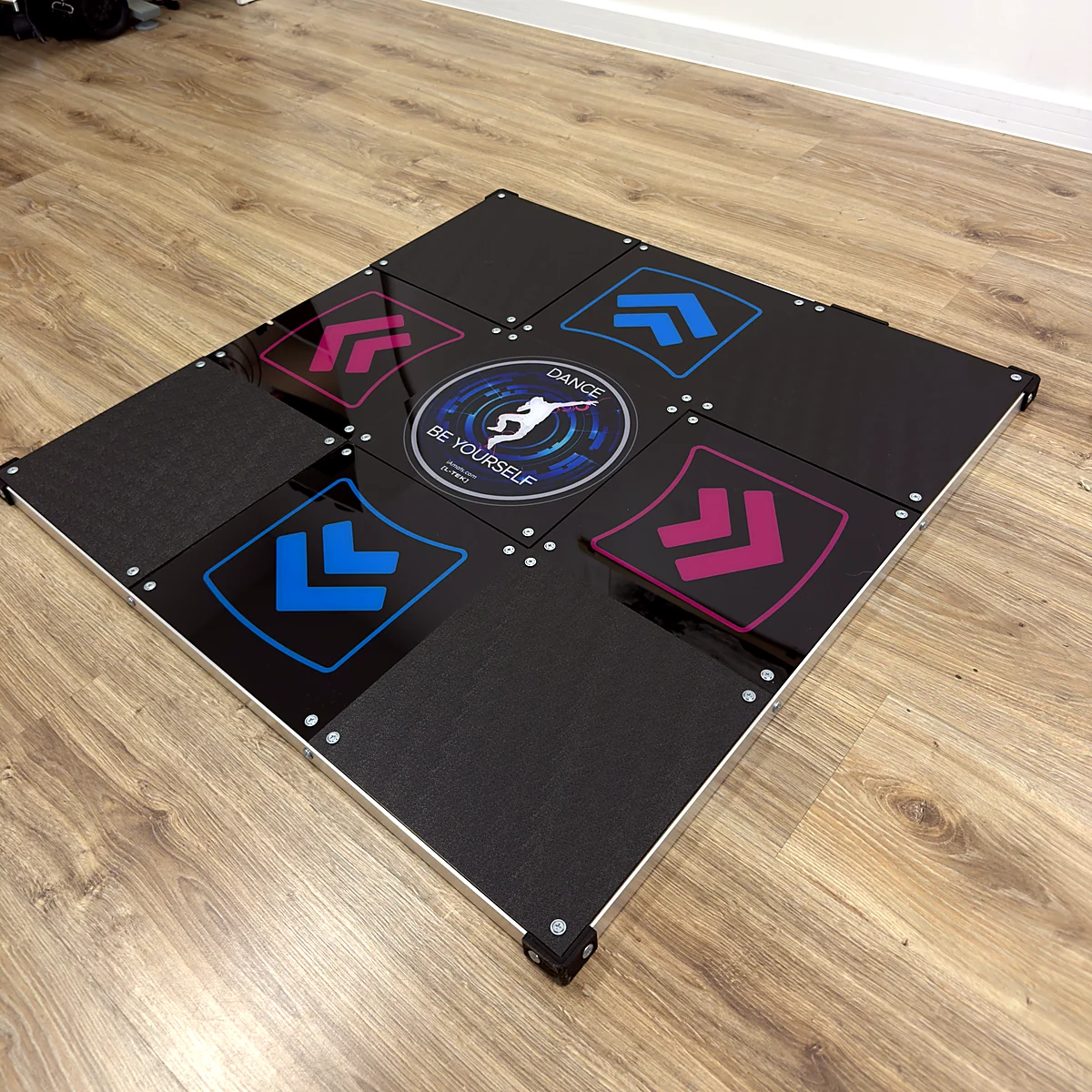 sq-ltek-core-dance-pad-in-room - Interactive Mats L-TEK L-TEK Core metal dance pad standing on a wooden floor in a living room, seen from the side
