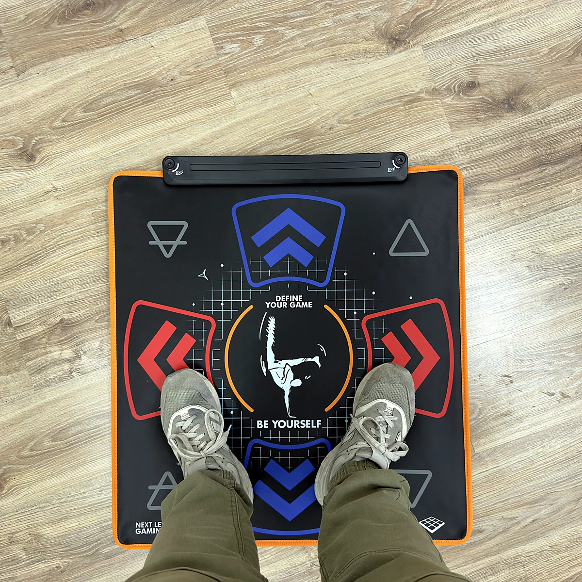 sq-nlgm-mat-in-use-top-view - Interactive Mats L-TEK Person standing in trainers on the L-TEK Next Level Gaming Mat on a wooden floor, seen from above
