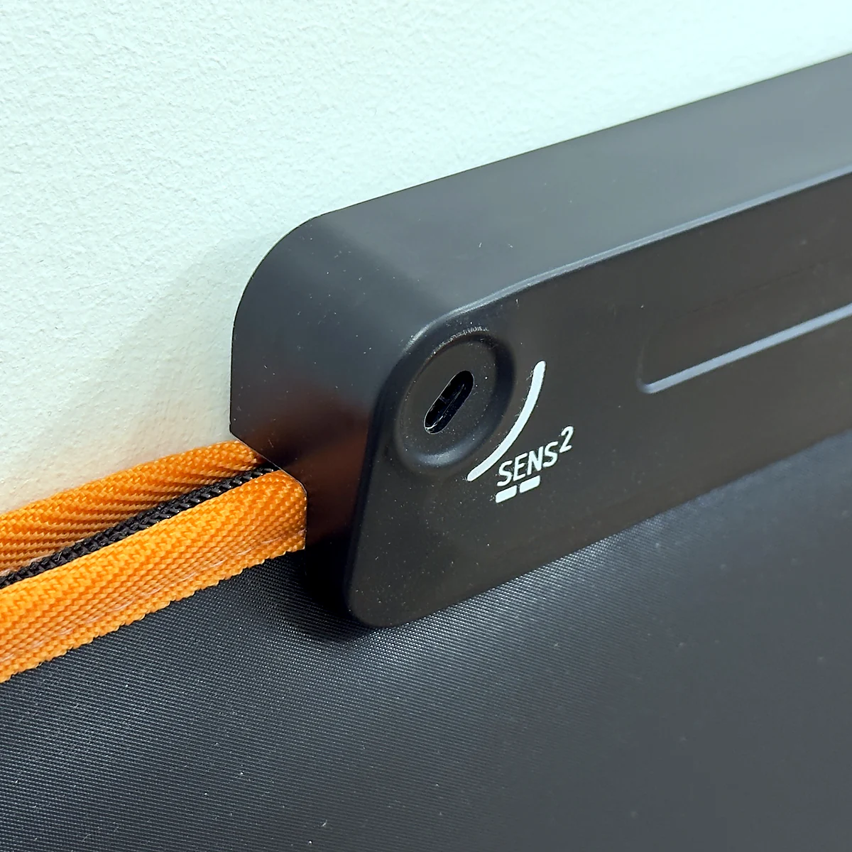 sq-nlgm-sensitivity-adjustment - Interactive Mats L-TEK Recessed sensitivity adjuster marked SENS with a scale, on the end of the Next Level Gaming Mat bar
