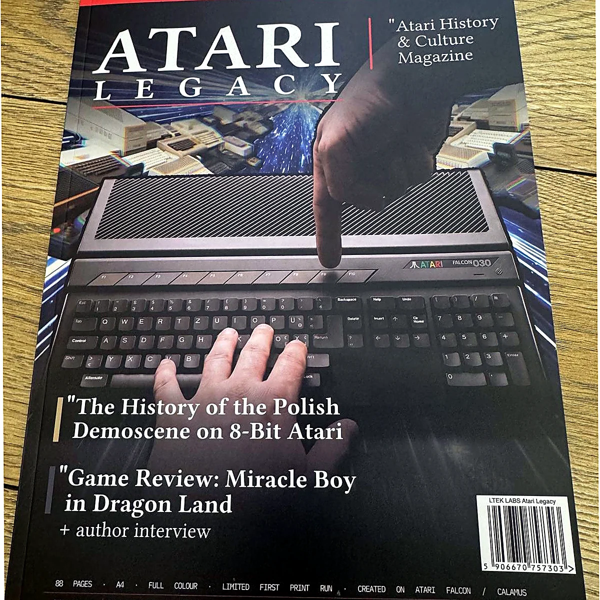 sq-nr01-cover-in-hand - Interactive Mats L-TEK Printed copy of Atari Legacy Issue 01 lying on a wooden desk, cover showing a hand on an Atari keyboard