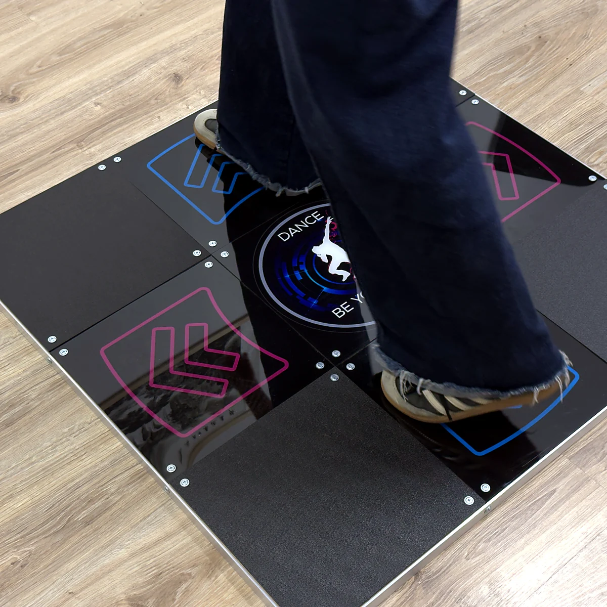 sq-prime-in-use-on-floor - Interactive Mats L-TEK Player standing on the L-TEK Prime metal dance pad placed on a wooden floor at home
